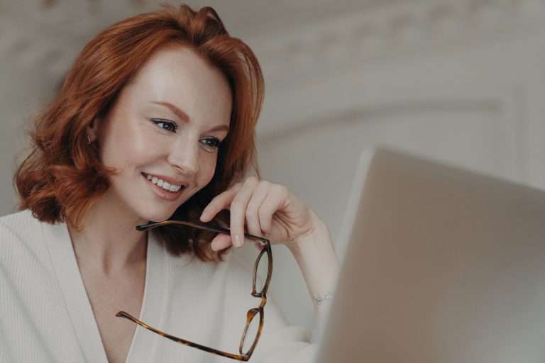 Rothaarige Webdesignerin verwendet Anwendung auf Laptop