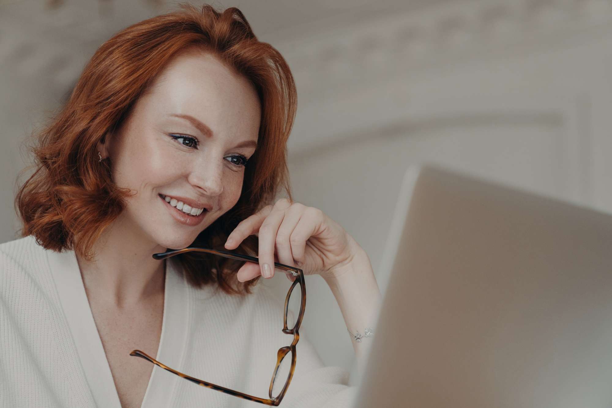 Rothaarige Webdesignerin verwendet Anwendung auf Laptop